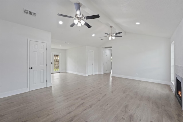 unfurnished living room with a tiled fireplace, ceiling fan, lofted ceiling with beams, and light wood-type flooring