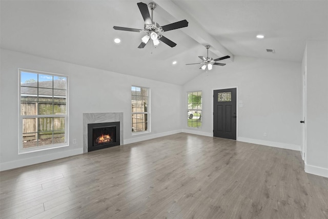 unfurnished living room with ceiling fan, lofted ceiling with beams, light hardwood / wood-style floors, and a high end fireplace