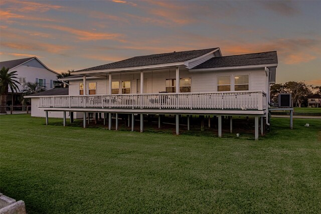 back house at dusk featuring a yard, central AC, and a wooden deck