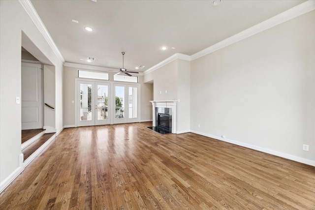 unfurnished living room with baseboards, a ceiling fan, a premium fireplace, ornamental molding, and wood finished floors