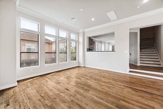 unfurnished living room with wood finished floors, visible vents, baseboards, stairway, and crown molding