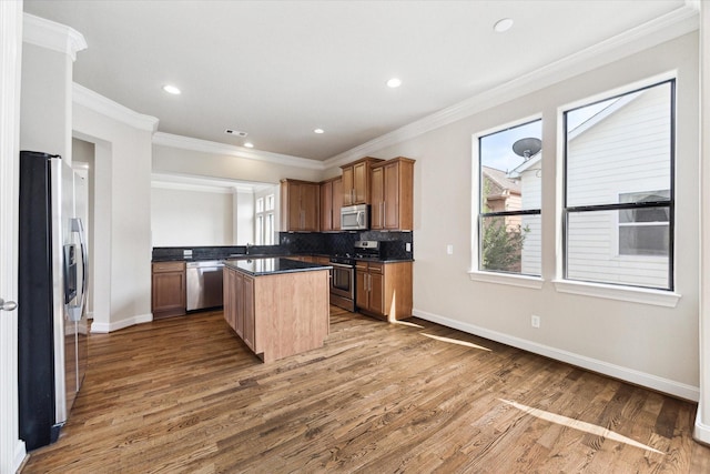 kitchen with tasteful backsplash, crown molding, a center island, and appliances with stainless steel finishes