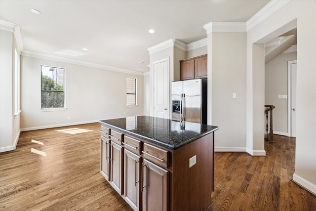 kitchen featuring a center island, stainless steel fridge, dark stone countertops, and wood finished floors