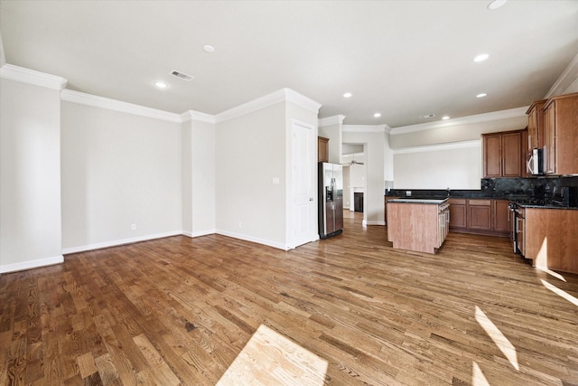 kitchen with decorative backsplash, crown molding, wood-type flooring, and appliances with stainless steel finishes