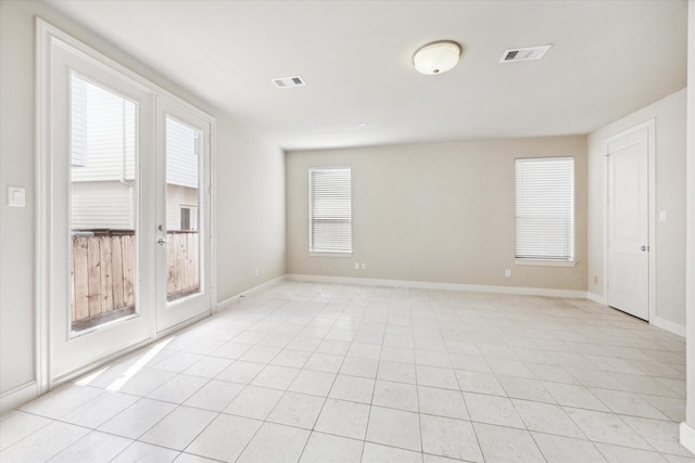 spare room with light tile patterned floors, french doors, visible vents, and baseboards