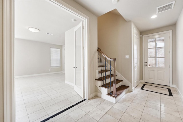 foyer entrance with light tile patterned floors, stairs, visible vents, and baseboards