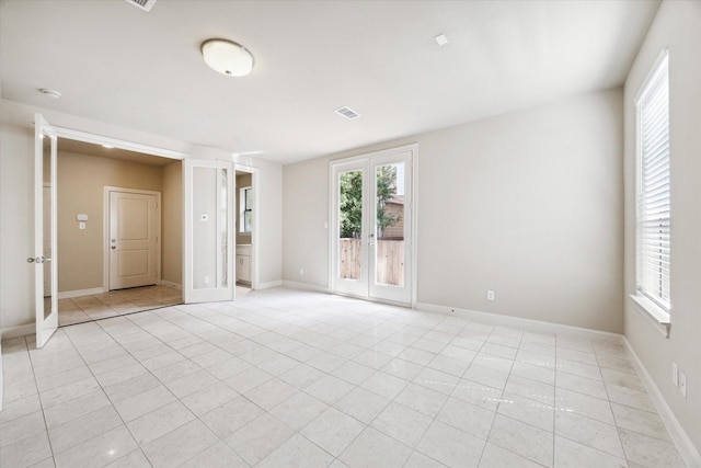 empty room with french doors, visible vents, baseboards, and light tile patterned floors