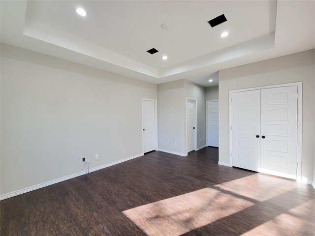 unfurnished bedroom with dark hardwood / wood-style flooring and a raised ceiling