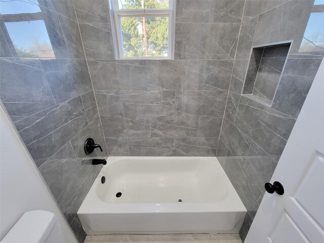 bathroom with tiled shower / bath combo and toilet