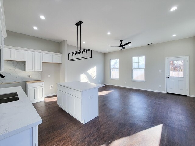 kitchen with ceiling fan, a center island, white cabinets, and decorative light fixtures