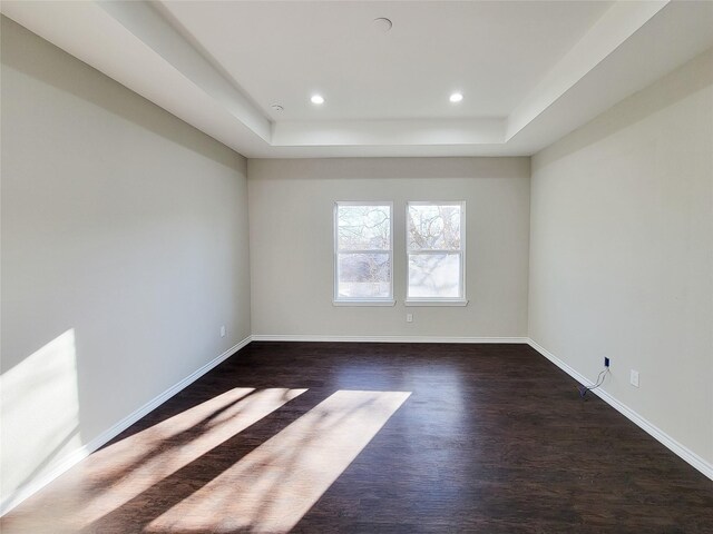 spare room with dark wood-type flooring and a tray ceiling