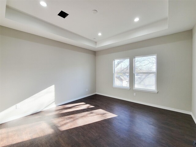 spare room with dark hardwood / wood-style flooring and a tray ceiling