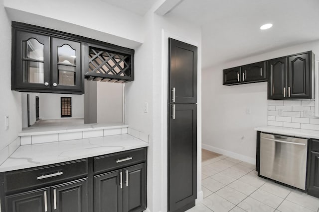 kitchen with appliances with stainless steel finishes, tasteful backsplash, light tile patterned floors, and light stone counters