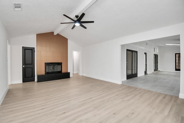 unfurnished living room featuring ceiling fan, a fireplace, lofted ceiling with beams, and light hardwood / wood-style flooring