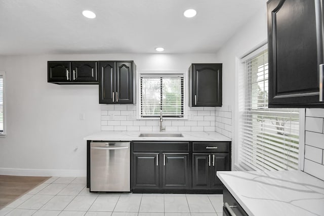 kitchen featuring light stone countertops, sink, stainless steel dishwasher, decorative backsplash, and light tile patterned floors