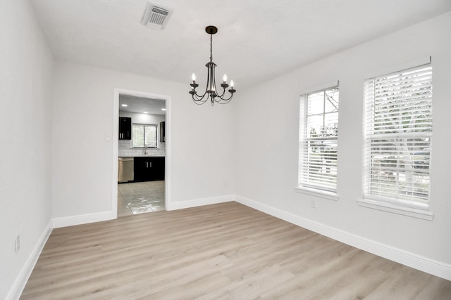 unfurnished dining area featuring light hardwood / wood-style flooring and an inviting chandelier