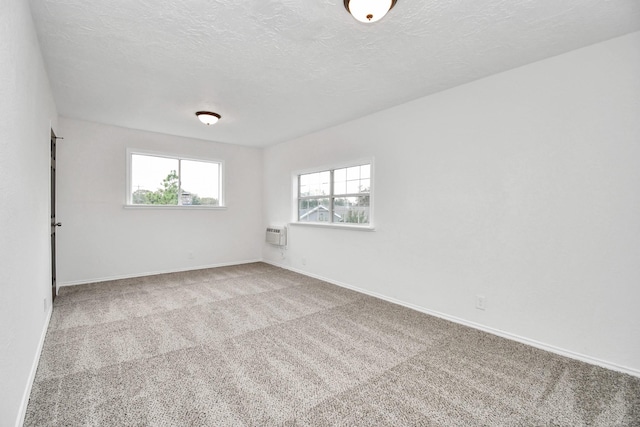 carpeted spare room with a wall mounted AC and a textured ceiling