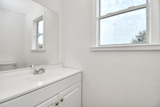 bathroom featuring vanity, toilet, and a healthy amount of sunlight