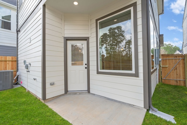 property entrance featuring a patio, a lawn, and central air condition unit