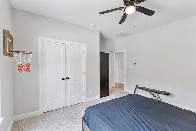 bedroom with ceiling fan, light carpet, and a closet