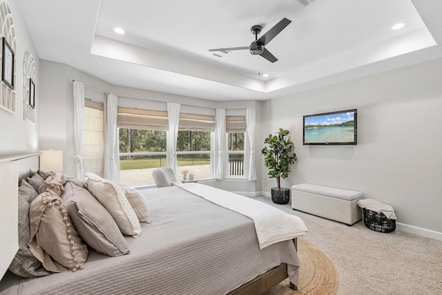 bedroom with carpet floors, a raised ceiling, and ceiling fan