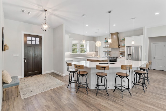 kitchen featuring stainless steel refrigerator with ice dispenser, white cabinets, a large island, and pendant lighting