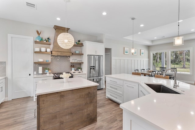 kitchen with appliances with stainless steel finishes, white cabinetry, hanging light fixtures, and sink