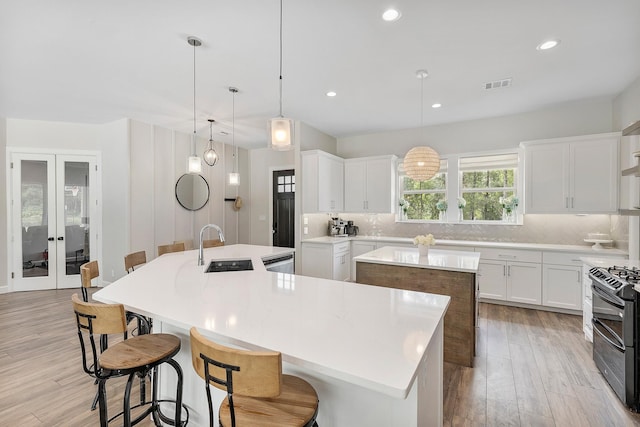 kitchen featuring white cabinetry, a large island, sink, and decorative light fixtures