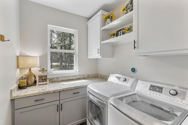 clothes washing area with washer and dryer, a healthy amount of sunlight, and cabinets