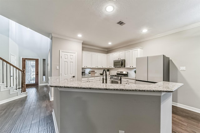 kitchen featuring white cabinets, appliances with stainless steel finishes, light stone countertops, and a spacious island