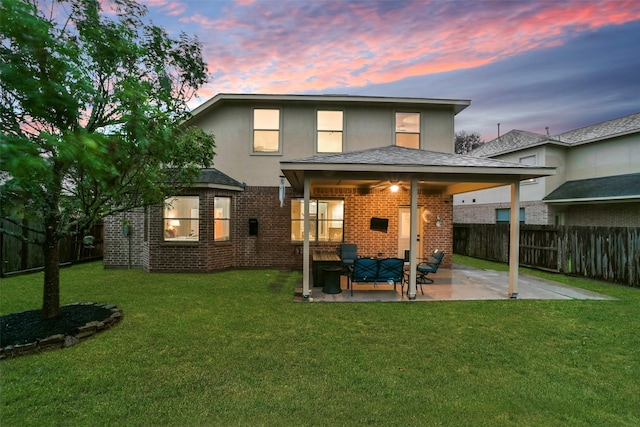 back house at dusk featuring a patio area, a yard, and an outdoor hangout area