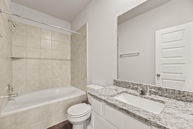 full bathroom featuring vanity, wood-type flooring, tiled shower / bath combo, and toilet