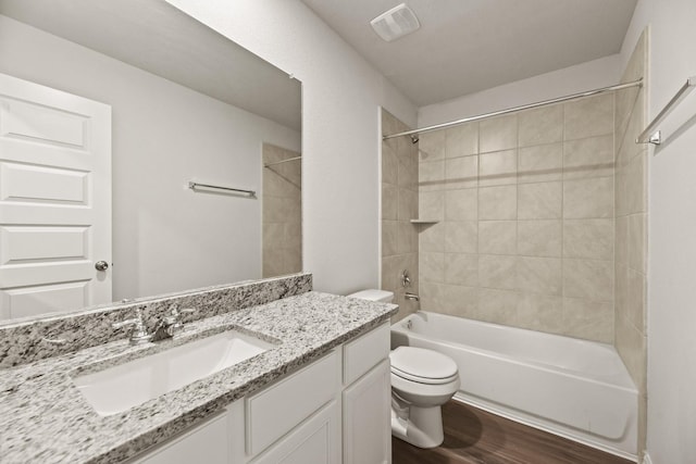 full bathroom with hardwood / wood-style floors, vanity, toilet, and tiled shower / bath