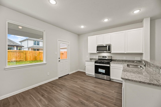 kitchen with white cabinets, sink, light stone countertops, and stainless steel appliances