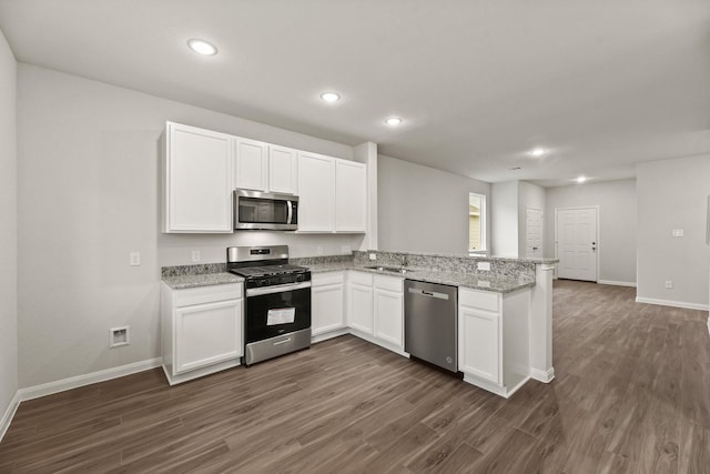 kitchen featuring dark hardwood / wood-style floors, light stone counters, white cabinetry, and appliances with stainless steel finishes