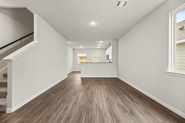 unfurnished living room with dark hardwood / wood-style flooring and a healthy amount of sunlight