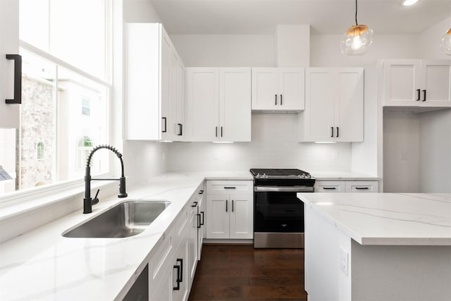 kitchen with electric range, sink, light stone counters, decorative light fixtures, and white cabinets