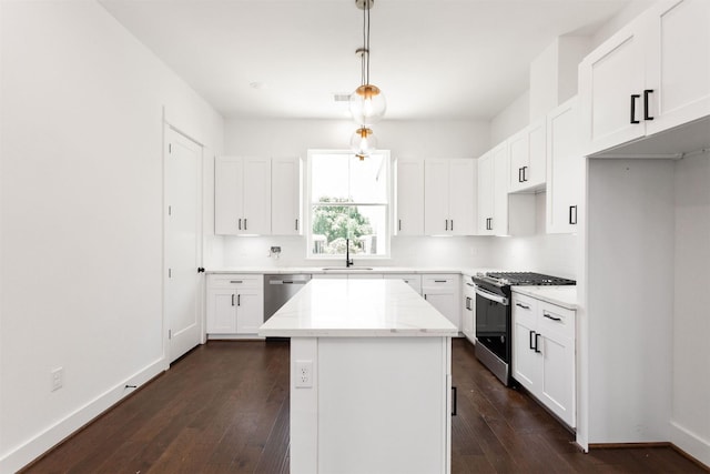 kitchen featuring stainless steel appliances, sink, decorative light fixtures, white cabinets, and a kitchen island