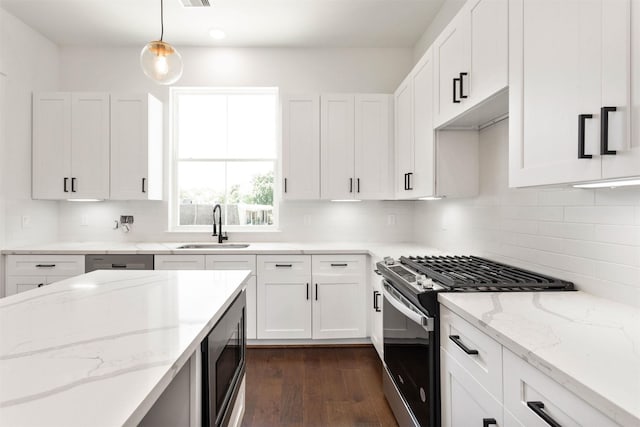 kitchen with built in microwave, sink, hanging light fixtures, white cabinets, and stainless steel range with gas stovetop