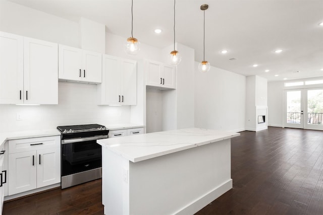 kitchen featuring electric range, light stone counters, white cabinets, and hanging light fixtures