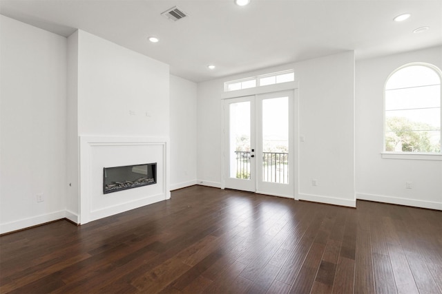 unfurnished living room with dark hardwood / wood-style flooring, a wealth of natural light, and french doors