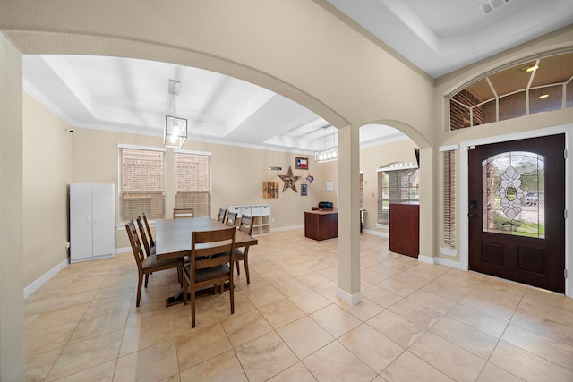 dining room with a raised ceiling, crown molding, and light tile patterned flooring