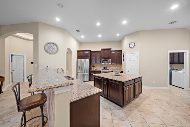 kitchen featuring light stone countertops, kitchen peninsula, stainless steel appliances, sink, and a breakfast bar area