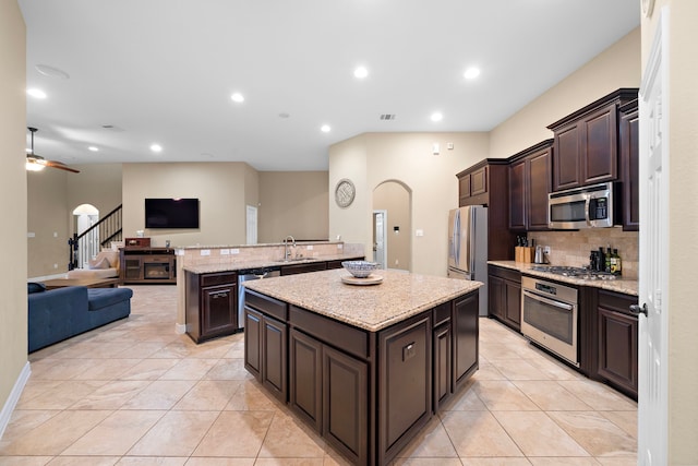 kitchen with a center island, ceiling fan, light tile patterned floors, appliances with stainless steel finishes, and dark brown cabinetry