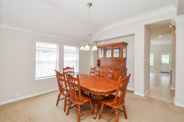 dining area with light carpet, lofted ceiling, an inviting chandelier, and crown molding