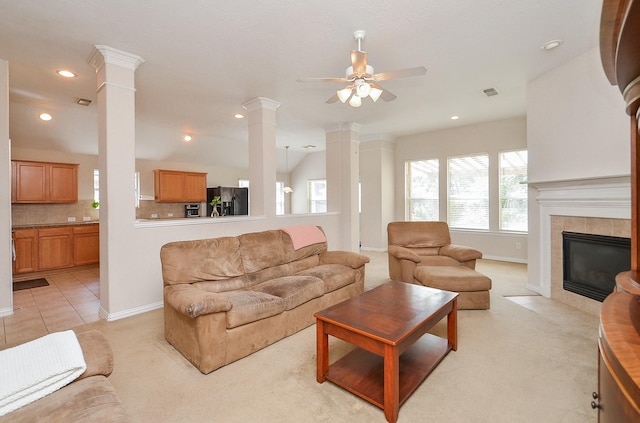 living room featuring lofted ceiling, ceiling fan, ornate columns, a fireplace, and light tile patterned flooring