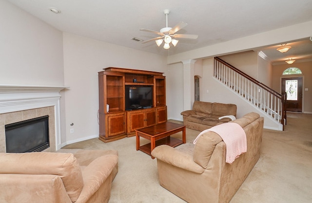 carpeted living room with a tile fireplace, ceiling fan, and ornamental molding