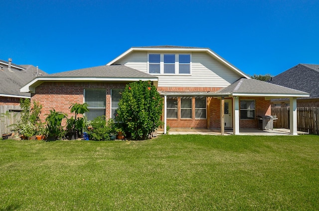 rear view of house featuring a lawn and a patio