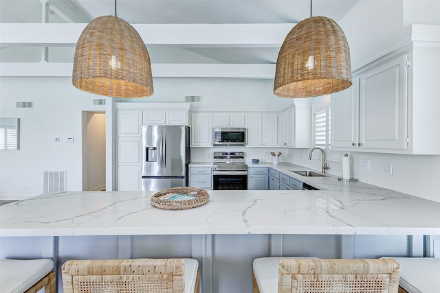 kitchen with pendant lighting, a kitchen bar, sink, and appliances with stainless steel finishes