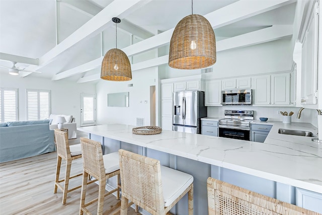 kitchen with sink, hanging light fixtures, light stone countertops, kitchen peninsula, and stainless steel appliances